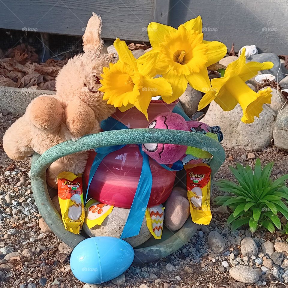 An Easter Egg Hunt with a basket filled with colorful Easter toys, candy,  and flowers for kids to find.