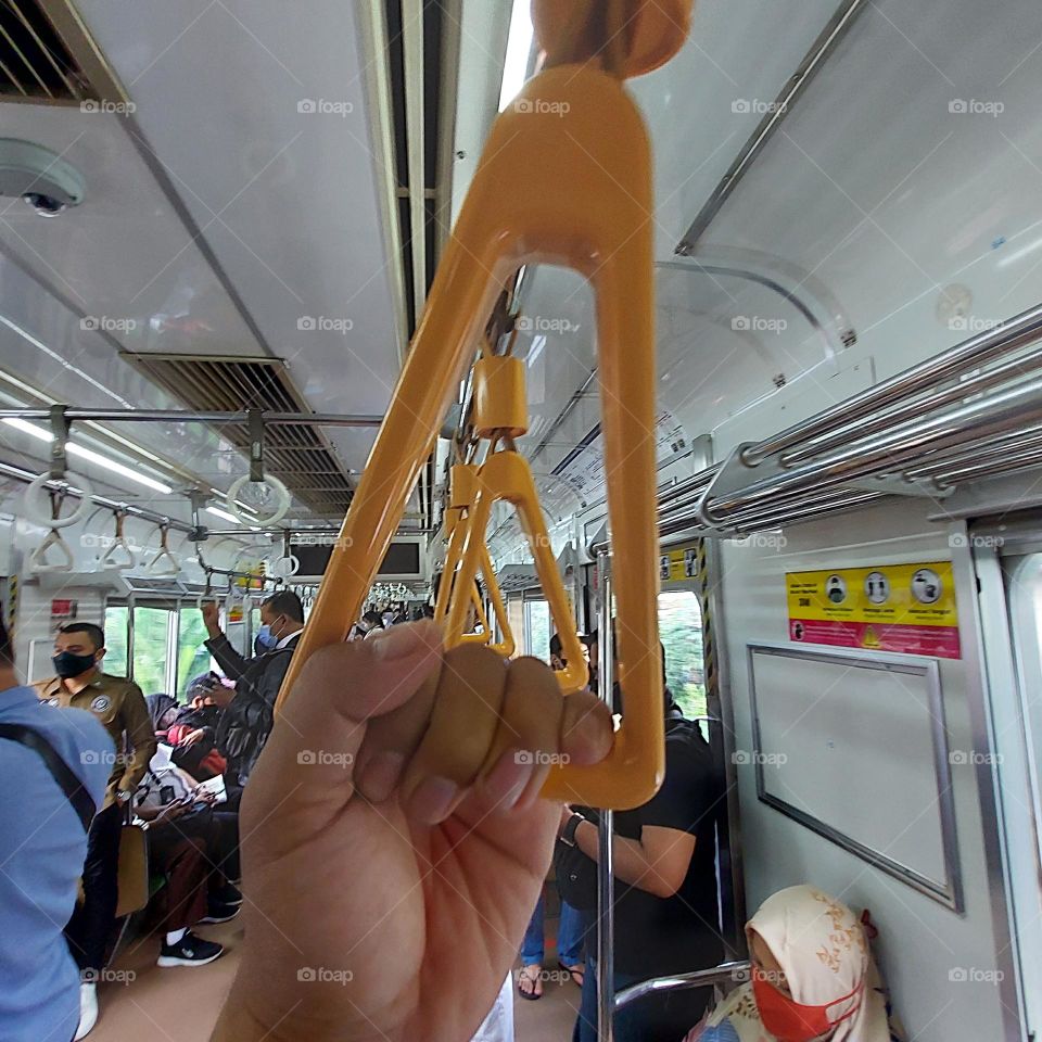 standing on the train, holding on to the hanger