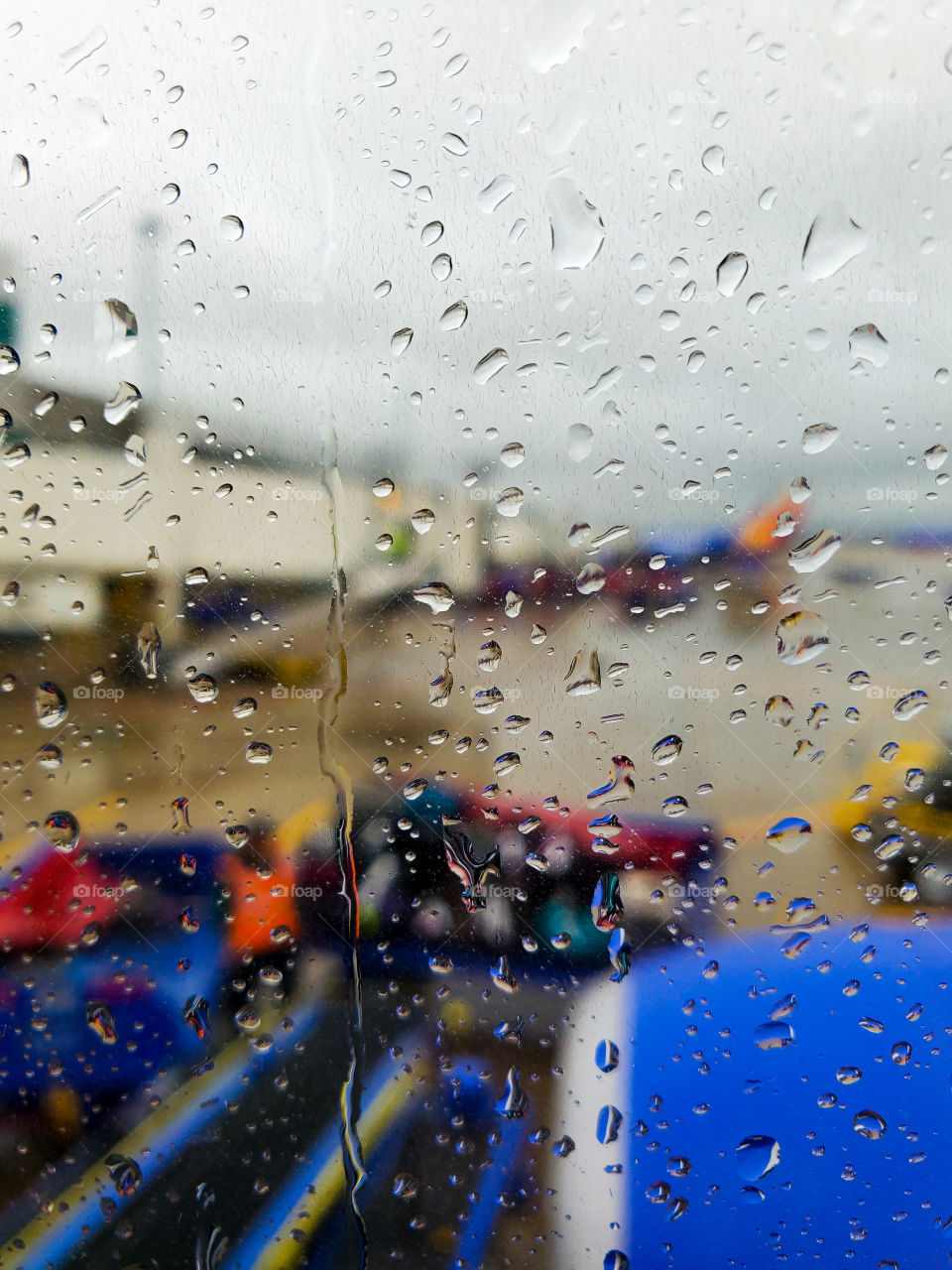 Looking out an airplane window, rain streaks the glass
