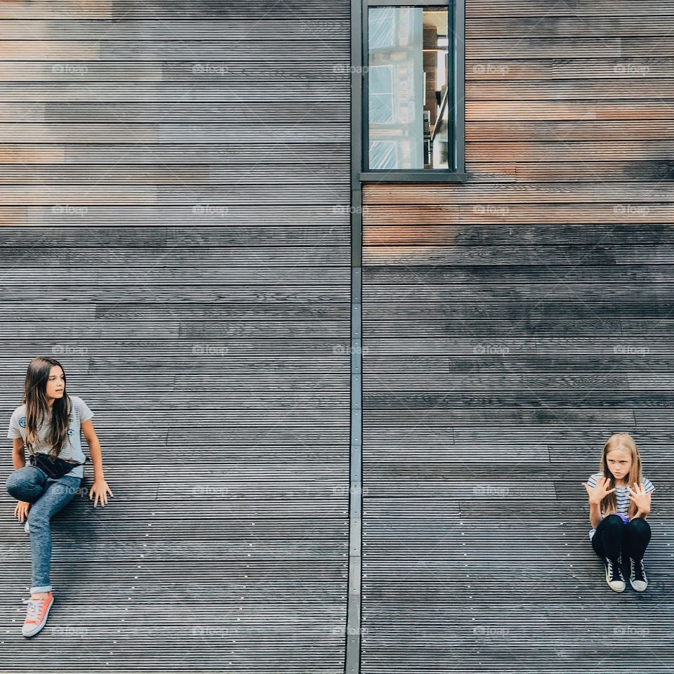 Two girls sitting near house window