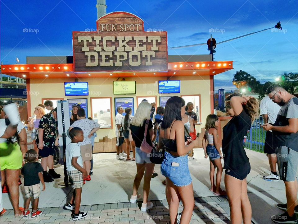 In line to get tickets, families gathering for a night at the amusement park.