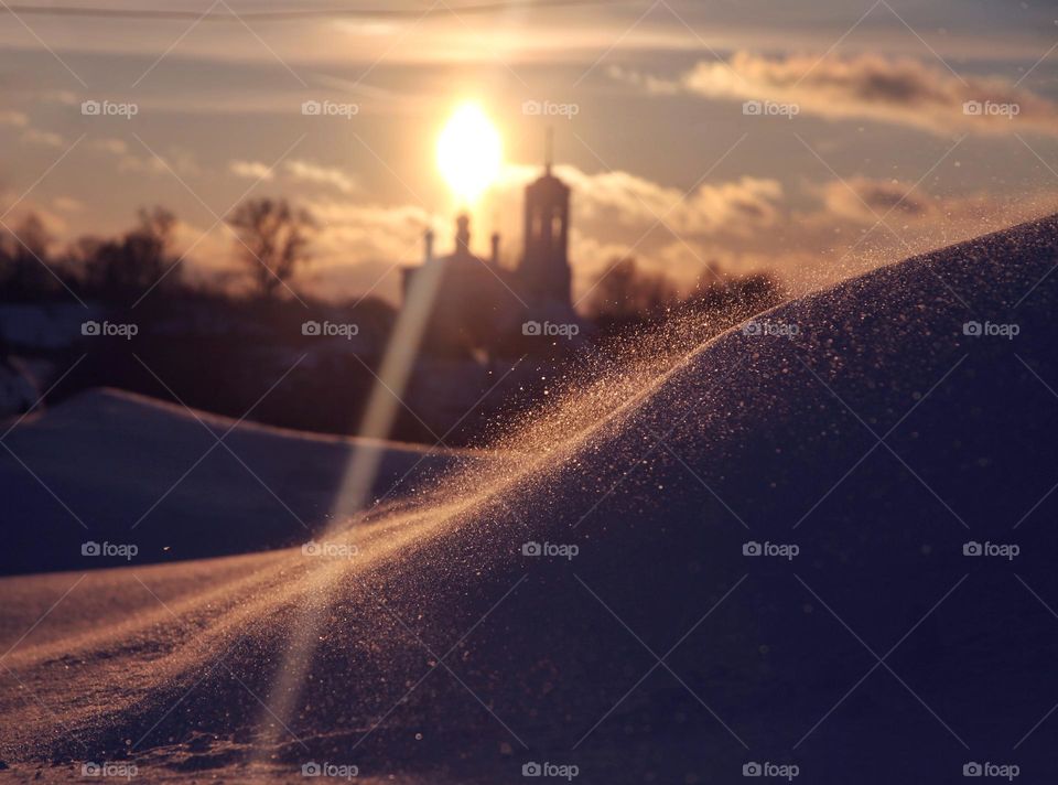 a snow whirlwind picks up sparkling snowflakes in the rays of the setting sun