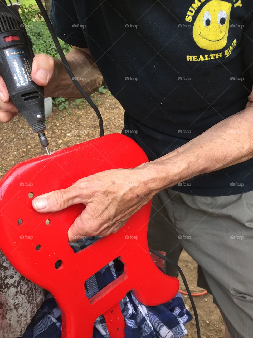 Man making a  4 string electric guitar by hand.