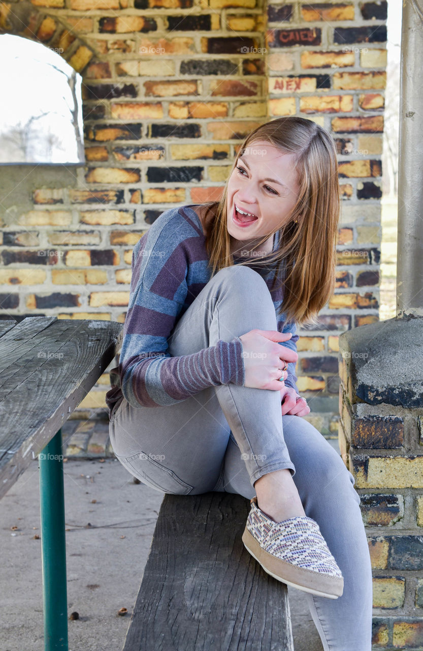 Young woman sitting on a park bench and laughing