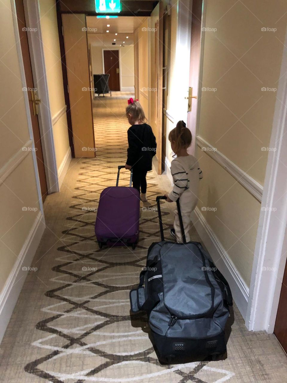 Two little girls leaving the hotel pulling the suitcases along with them ‘ so cute 💕
