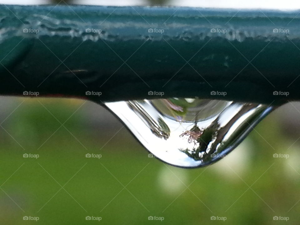 Raindrop falling from metal railing