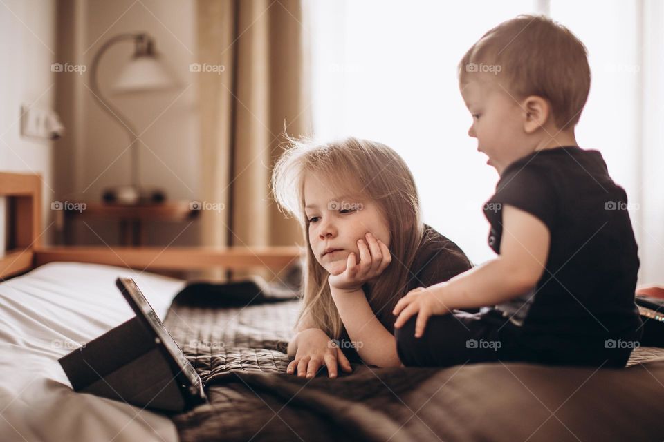 children sit on the bed and watch cartoons