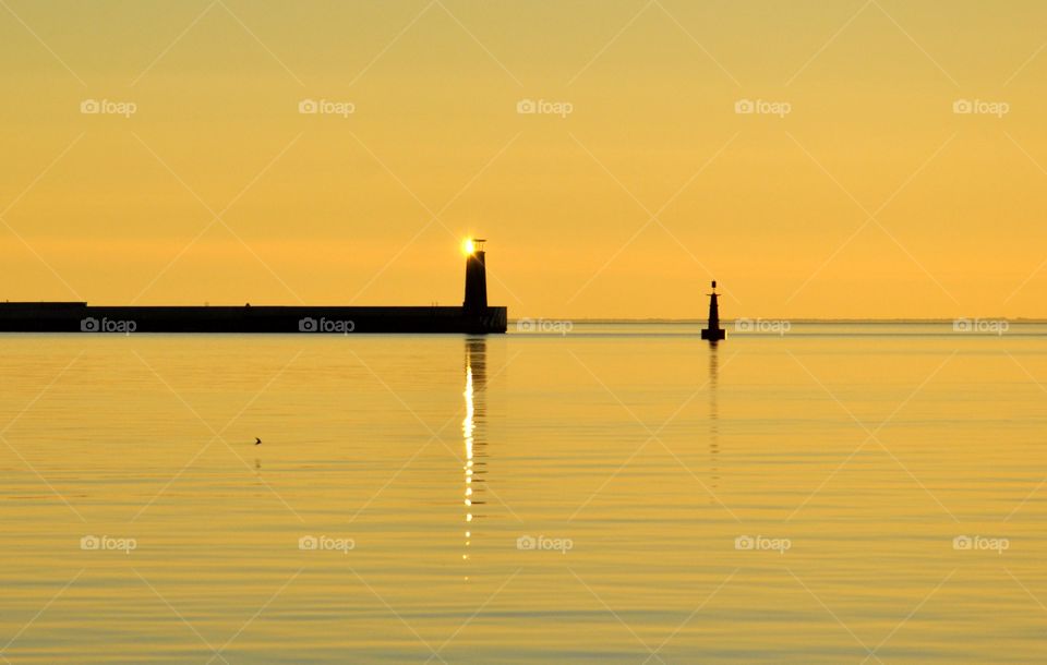 Sun reflecting in lighthouse during sunrise in Gdynia 