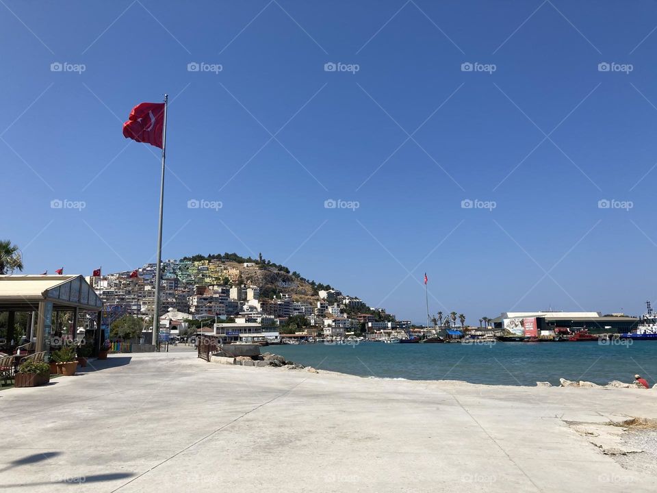 Summertime in Kusadasi, Turkey. Sunny day in charming sunny city. Ocean and blue sky. Colorful lovely city of Turkey. Summer vacation trips are my favorite. Mountain in the background.