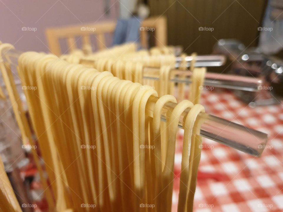 a portrait of fresh italian pasta drying on a pasta rack so it can be cooked a bit later.