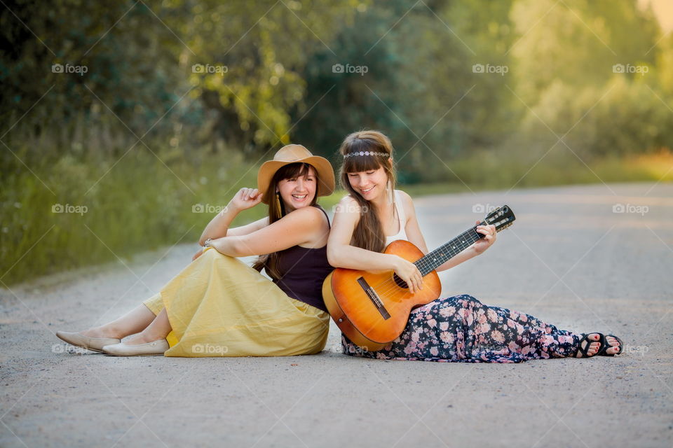 Young beautiful bohemian style women with guitar on the road