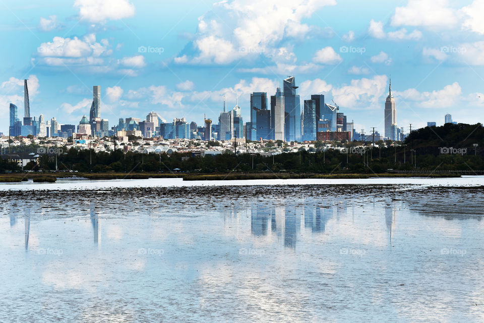 In the merky, swamp, and marshland waters of East Rutherford in New jersey the New York city skyline that stands tall in the distance still cast its reflection.