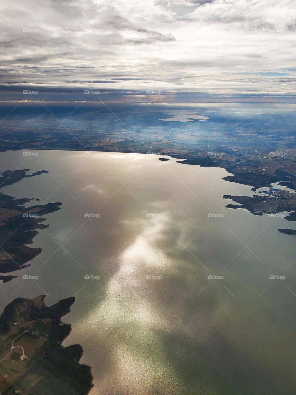 The sun creates an interesting design in the clouds and on a lake on a cool winter day from 15,000 feet