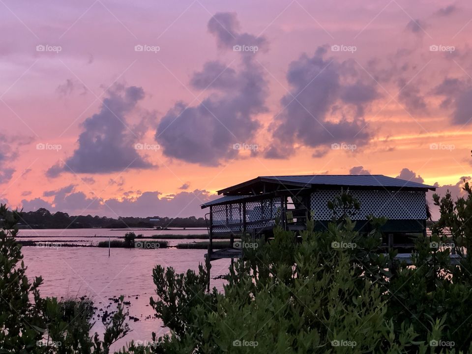 Sunset on the bayou with wooden house on stilts