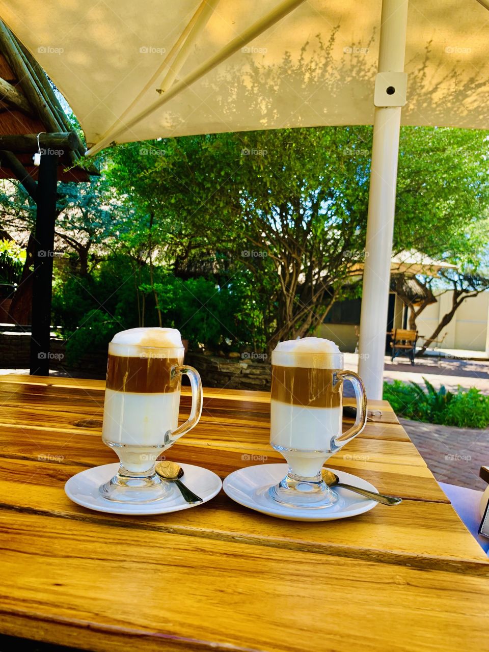 Two cups of double layered cups of Caffe latte coffee at an outside table at a restaurant. 