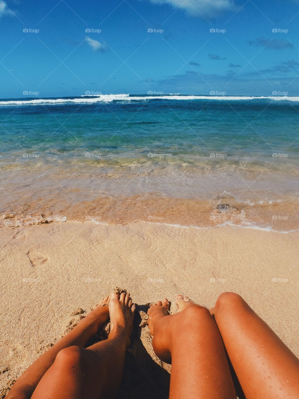 Tan legs relaxing on the beach in Hawaii.
