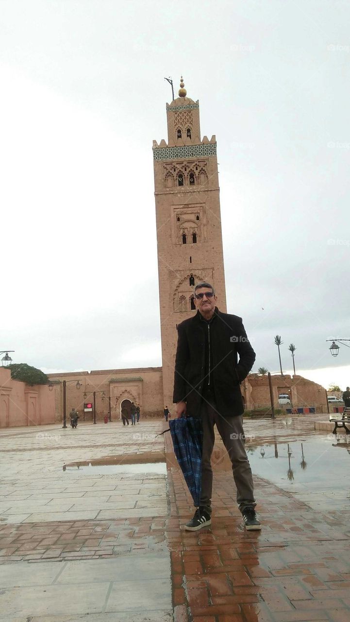 I m standing in famous square and minaret mosque in marrakech Morocco.