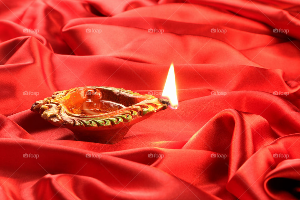 Indian festival Diwali diya oil lamp on red satin background