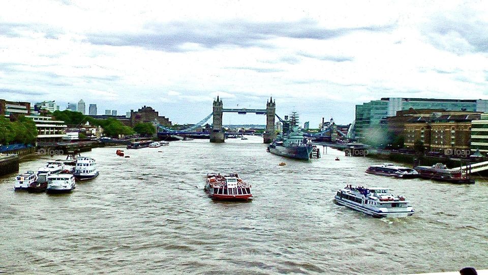 Ferry boats carrying passengers through the Thames River under London Bridge 