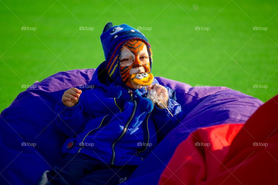 Face painted child eating a lollipop