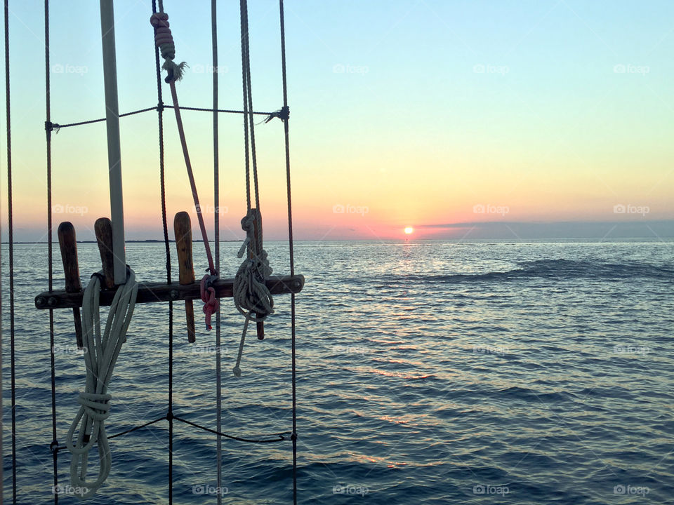 Pink sunset view from sailboat and ropes
