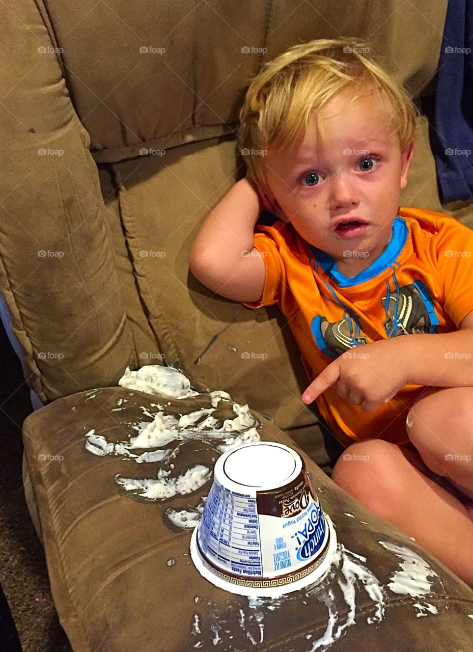 Boy showing yogurt on sofa