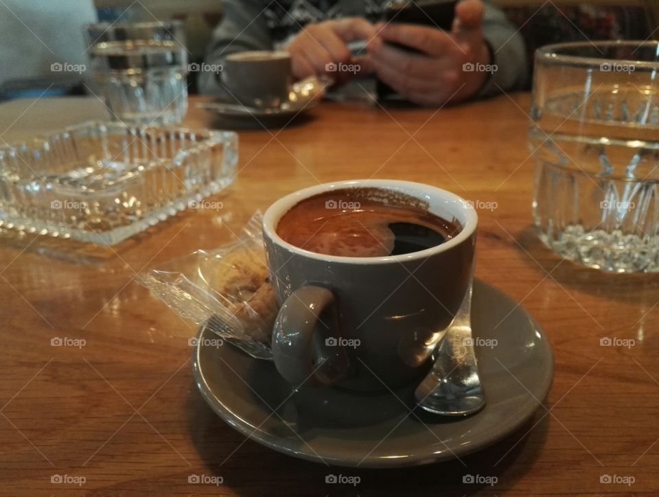 two long espresso cups and a man on the phone in the background
