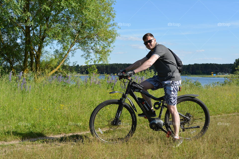 men ridding on a bike summer time, lake shore view