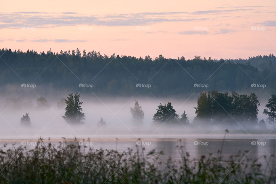 Foggy summer landscape by the lake in Finland after sunset