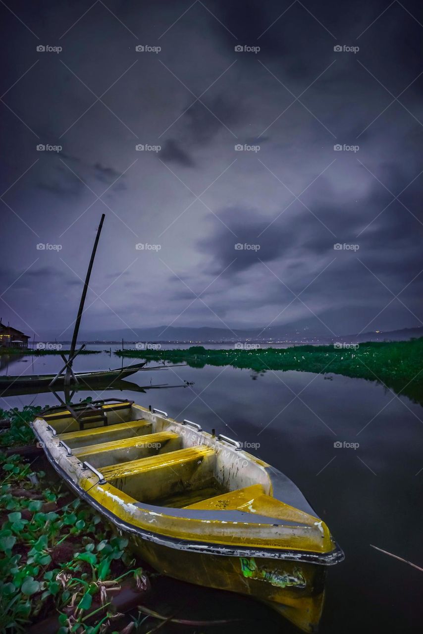 fishing boat leaning on the edge of the lake