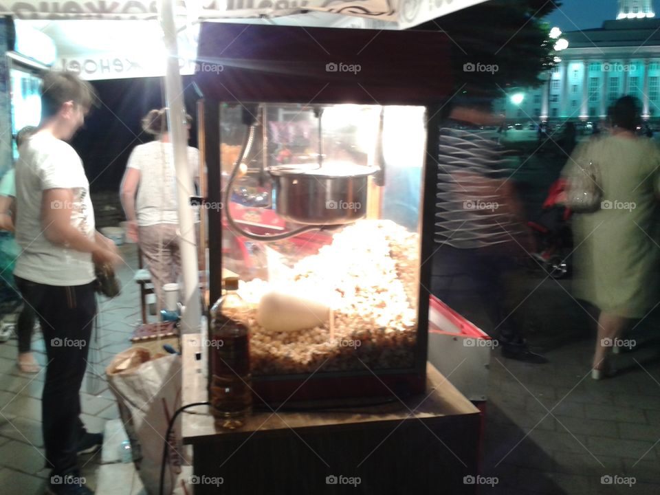 the apparatus of popcorn in a shop on the street of the city on a summer evening on Sunday.