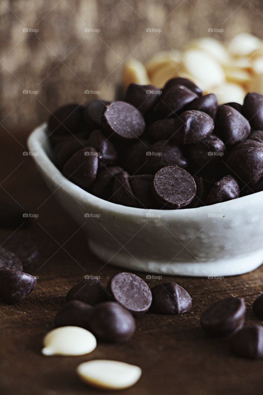 Close up dark chocolate chips with white chocolate chips at the background 
