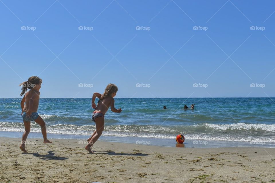 two little girls playing at the ocean