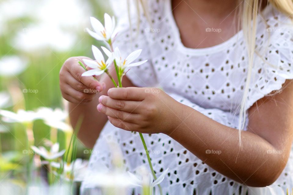 Kid holding hands white flowers in park at hot summer day