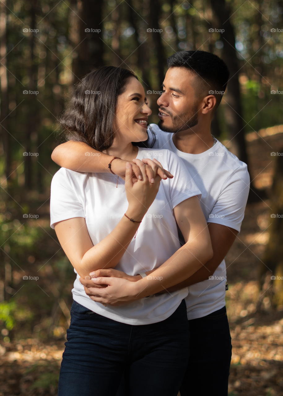 Couples of young people sitting in middle of the forest while looking happy into their eyes, in a sunny day.