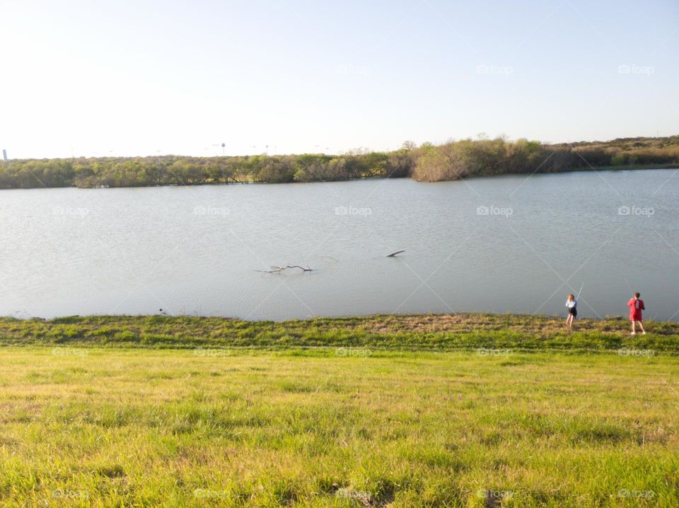 Young woman and man fishing at city park pond.