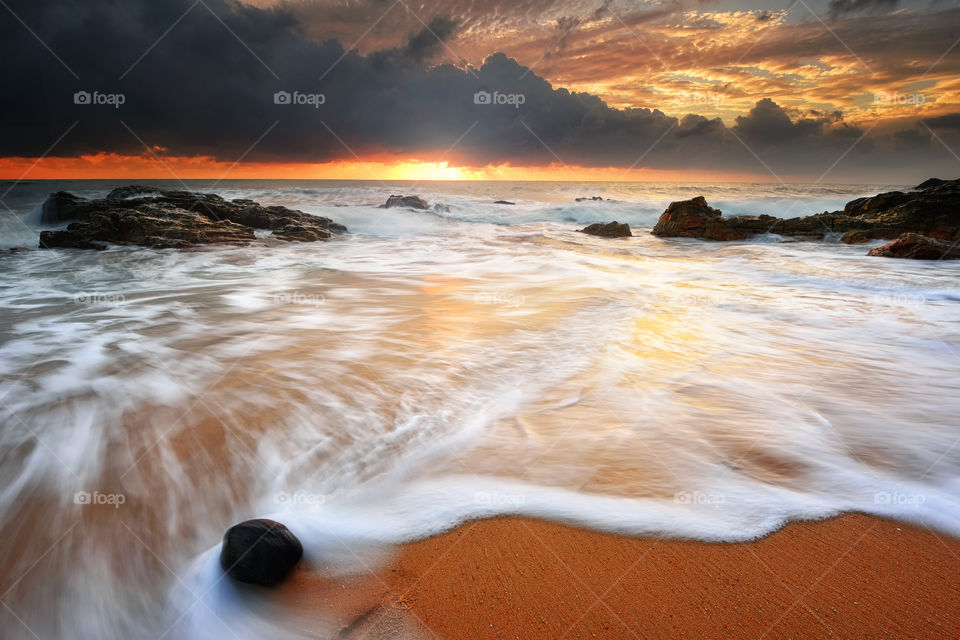 Beautiful sunrise over the beach with motion waves and dramatic sky