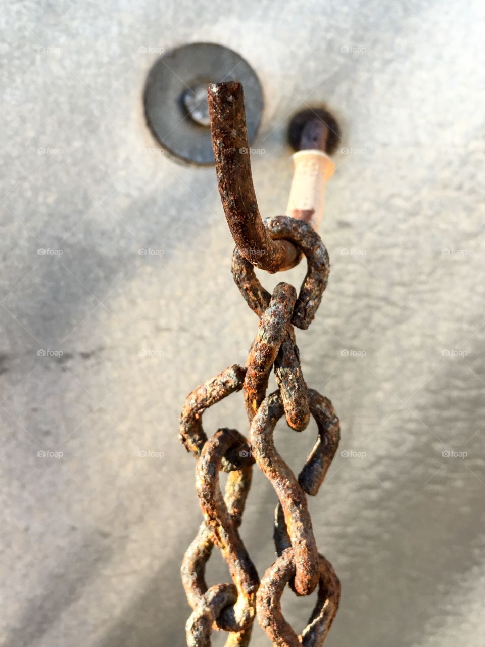 Antique old rusted chain hanging from hook
Closeup image