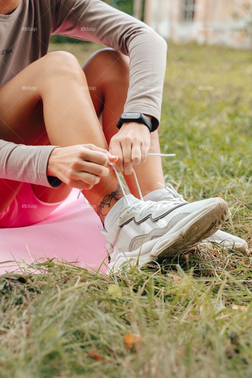 Woman bouncing sneakers after fitness exercise. Tattoo on leg 