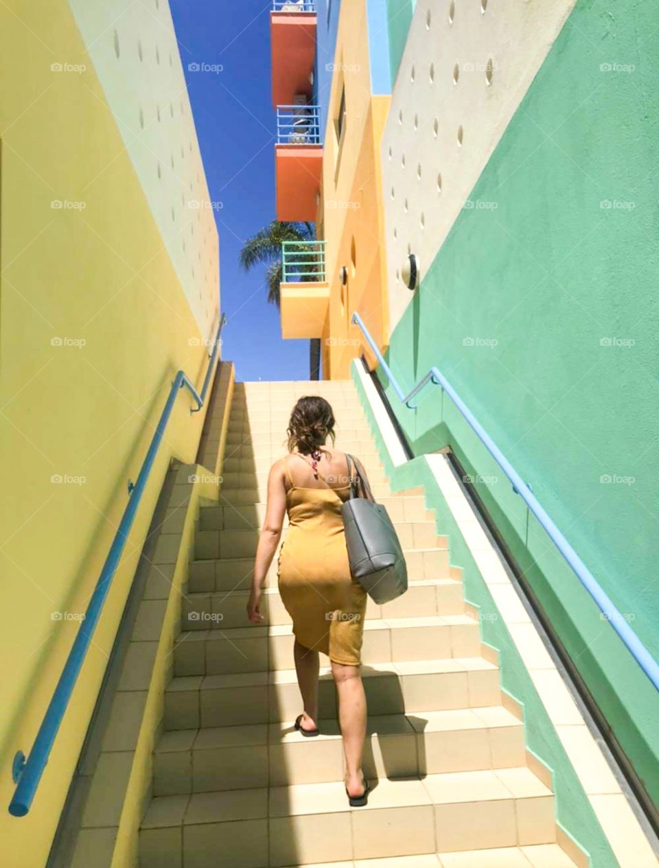 A girl in a yellow dress walks up the steps of a street in Albufeira.