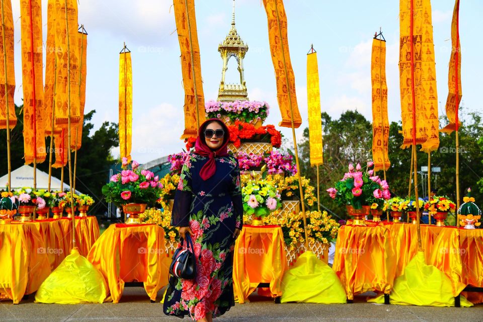 Portrait of a beautiful mother wearing a red hijab, wearing a floral patterned robe and wearing black glasses, taking a photo with a happy expression.