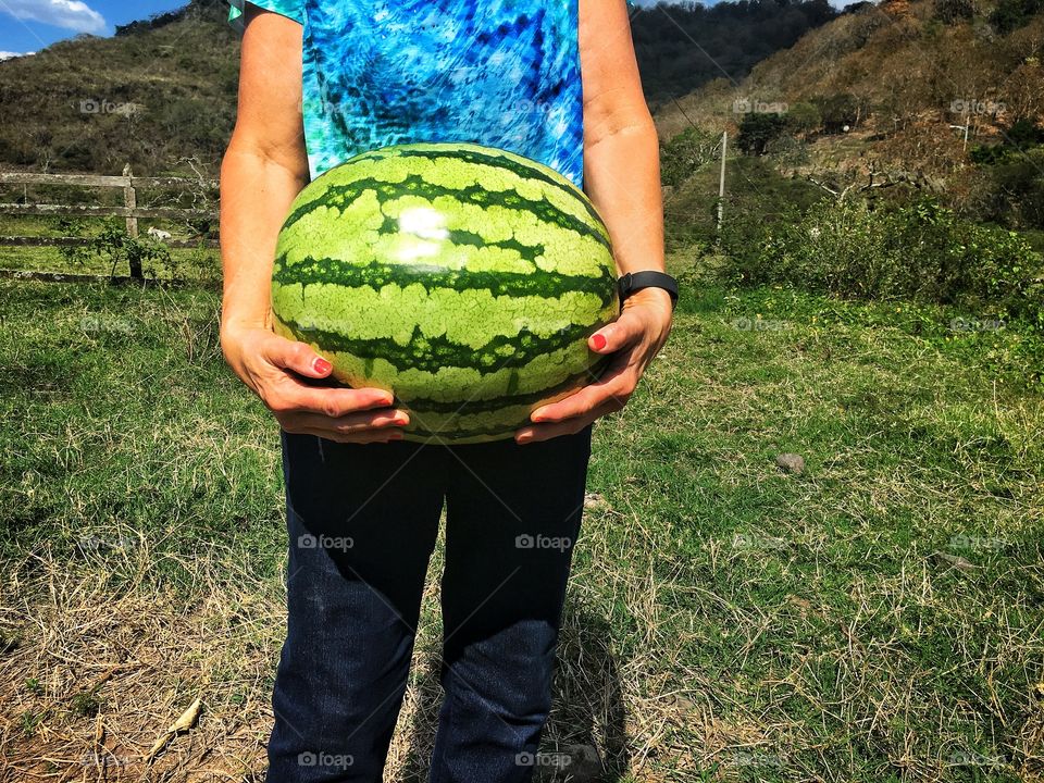 Holding watermelon while standing.