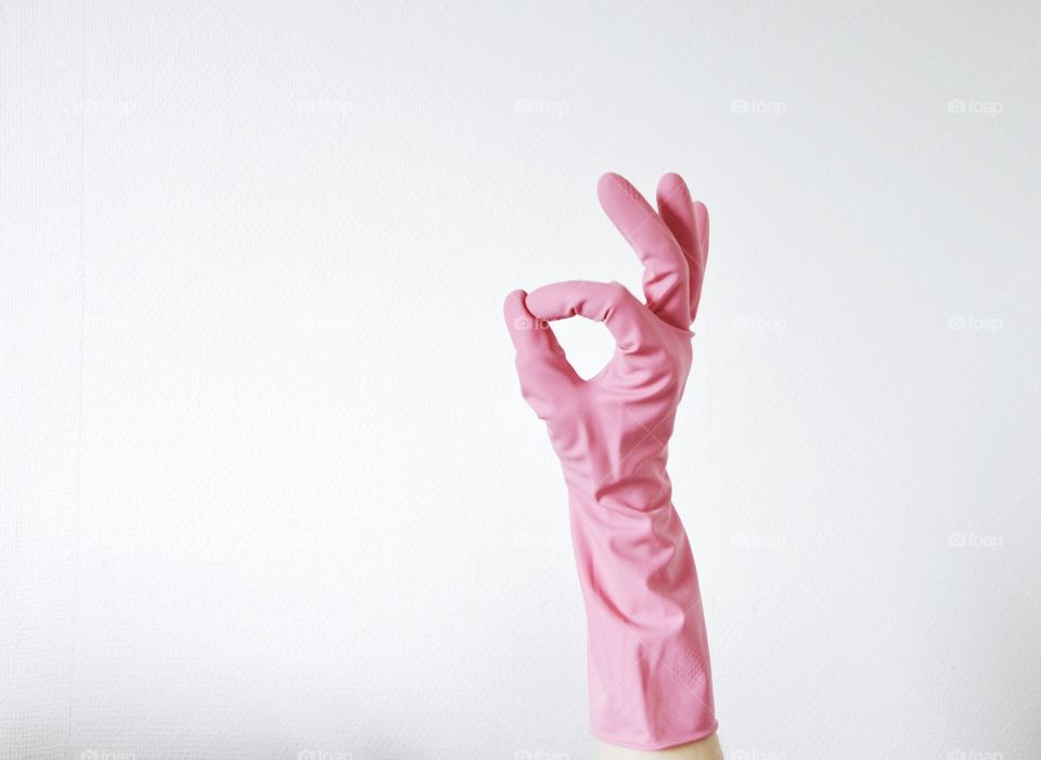 Photo of a pink glove on a hand doing a hand sign