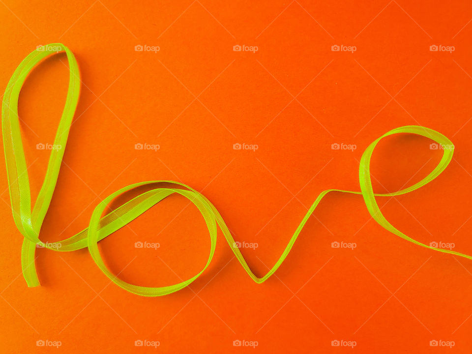 The word love in yellow ribbon with a contrasting bright orange background.