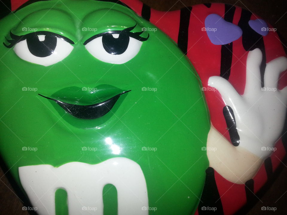 Green M&M waving. the lid to a ceramic trinket box