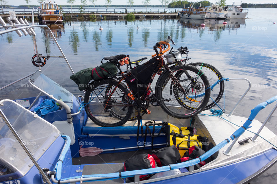 Taipalsaari, Finland – July 2, 2015:  Two touring bikes tied securely to a fishing boat with colorful panniers on the boat floor by the lake Saimaa, Finland for crossing to the other side of the lake from Taipalsaari on 2 July 2015.