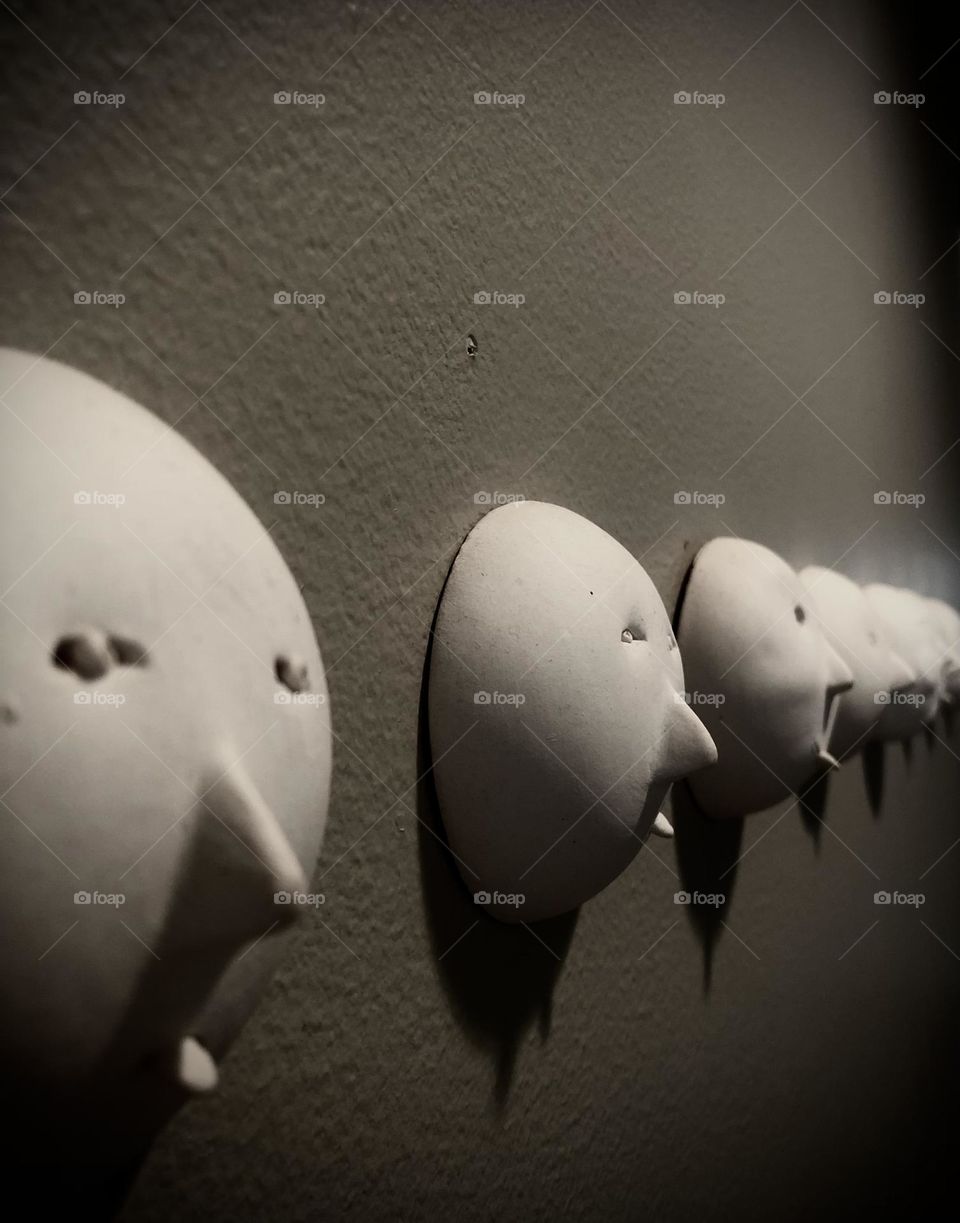 Multiverse. Black and white of wall art. Ceramic faces in a row; all of them are a little different from the other. 