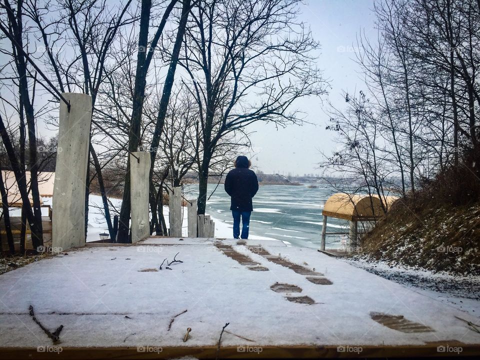 Man walking on stairs outside leaving footsteps in the snow 