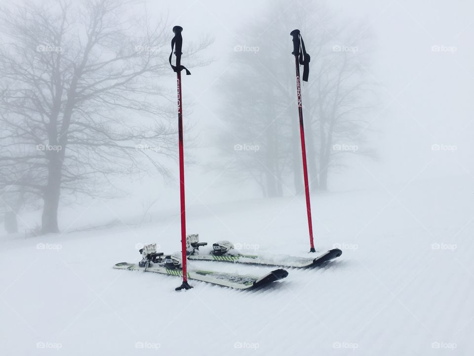 Skis and ski poles on the slope on a foggy day