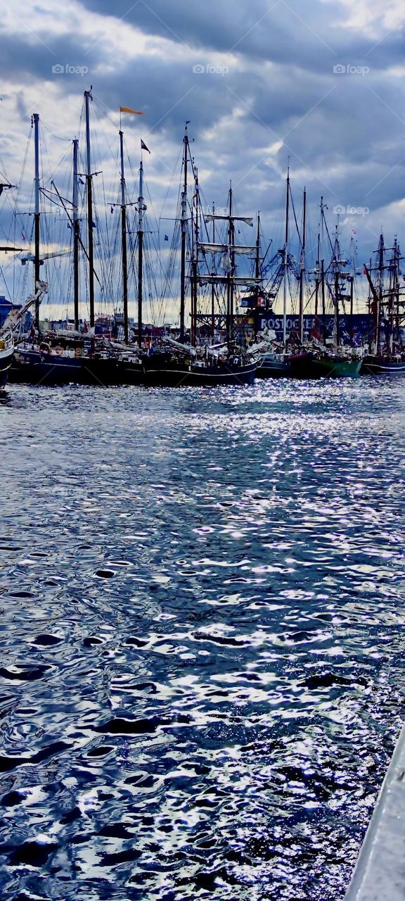 Several large sailboats are in the water lining up for the „Hanse Sail“ in „Rostock“ by the „Baltic Sea“ or in „Warnemünde“ nearby, an annual regatta that presents sailboats old and new, even antique pirate ships. 2023. Hypnotic Productions